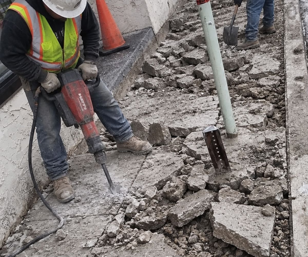 Construction worker removing deteriorated concrete during the sidewalk replacement project at 107 Lake Ave in Tuckahoe, NY.