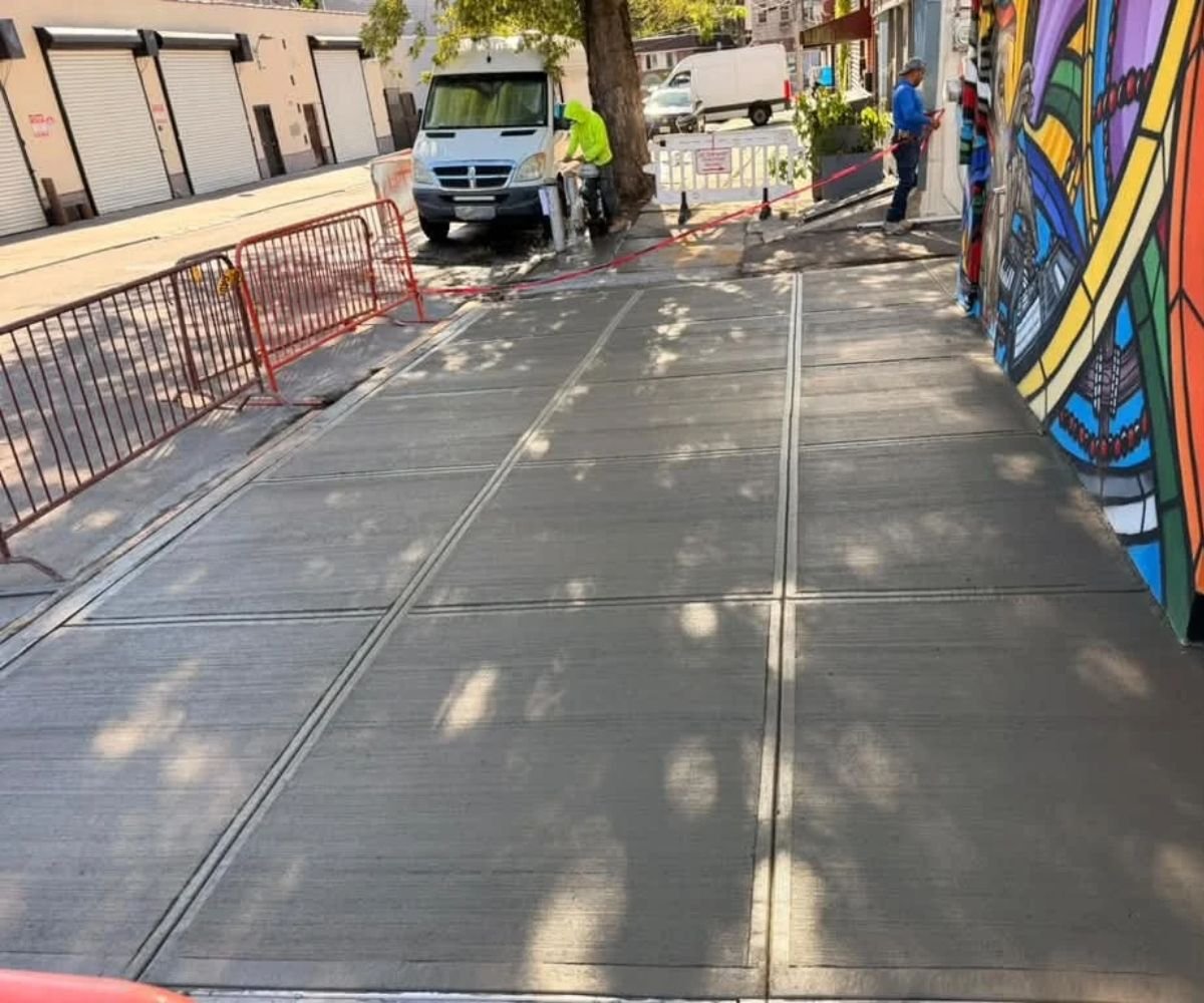 Newly replaced concrete sidewalk at 17 Division Pl in East Williamsburg, Brooklyn, featuring smooth, level slabs following a full-frontage sidewalk replacement project.