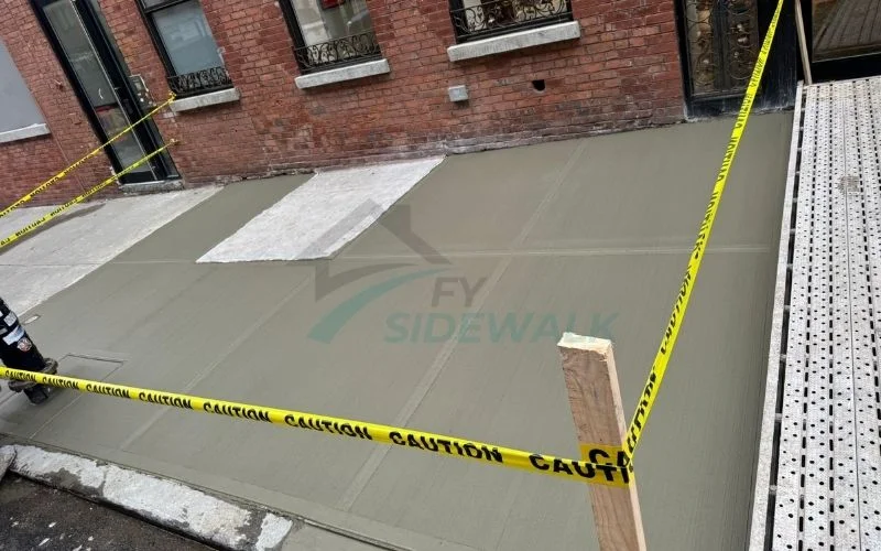 fresh sidewalk concrete beside a brick building in the bronx