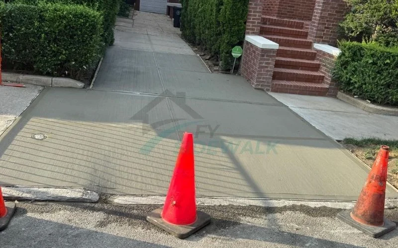 fresh concrete sidewalk repair near a residential driveway in queens
