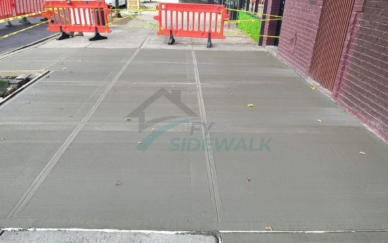 newly repaired sidewalk section with barriers at a bronx property